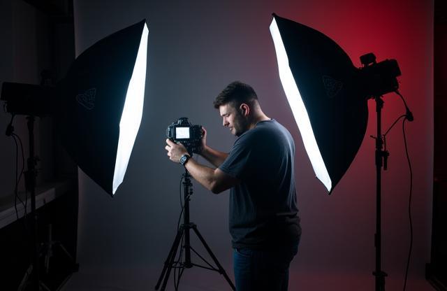 Photographer adjusting lighting setup during a professional studio shoot.
